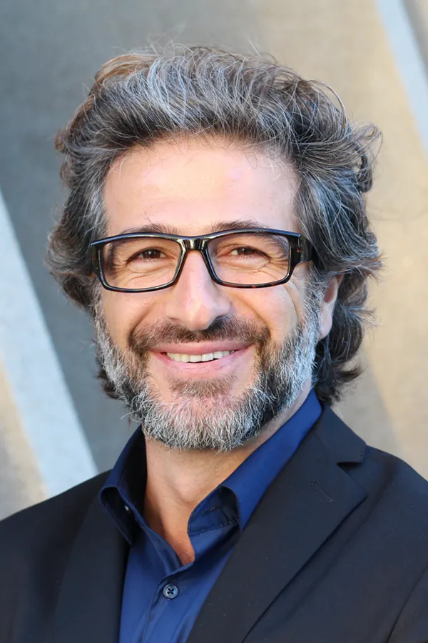 A man with glasses, salt and pepper hair and a beard smiling because he received treatment for andropause and low testosterone from The Cove Concierge Medicine in Denver.