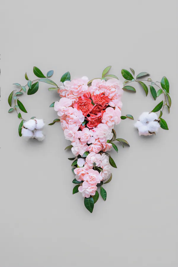Flowers on a gray background, arranged in the shape of the female reproductive system, representing Endometriosis treatment from The Cove Concierge Medicine in Denver.