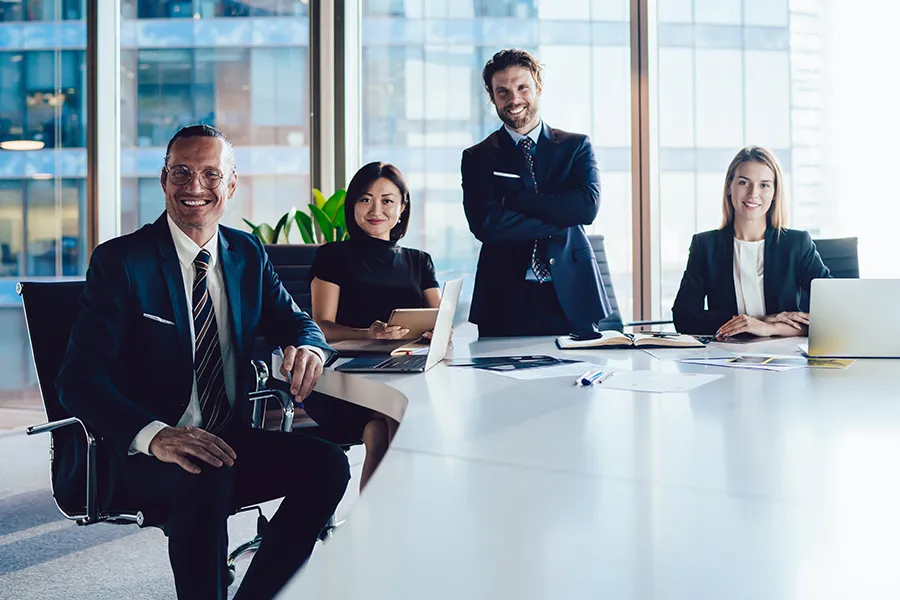 A group of healthy, focused executives sit happily meeting around a boardroom table. Schedule concierge primary care for executives from The Cove Concierge Medicine in Denver.