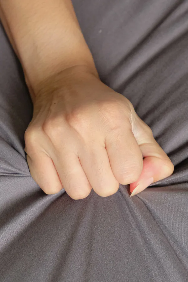 Close-up of a woman's hand grabbing a sheet, indicating sexual pleasure. Get female sexual dysfunction treatment from The Cove Concierge Medicine in Denver.