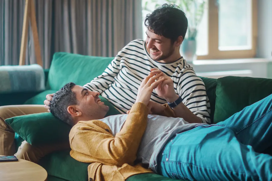 An LGBTQ+ couple lovingly relaxing on their couch. Schedule LGBTQ+ primary care from The Cove Concierge Medicine in Denver.